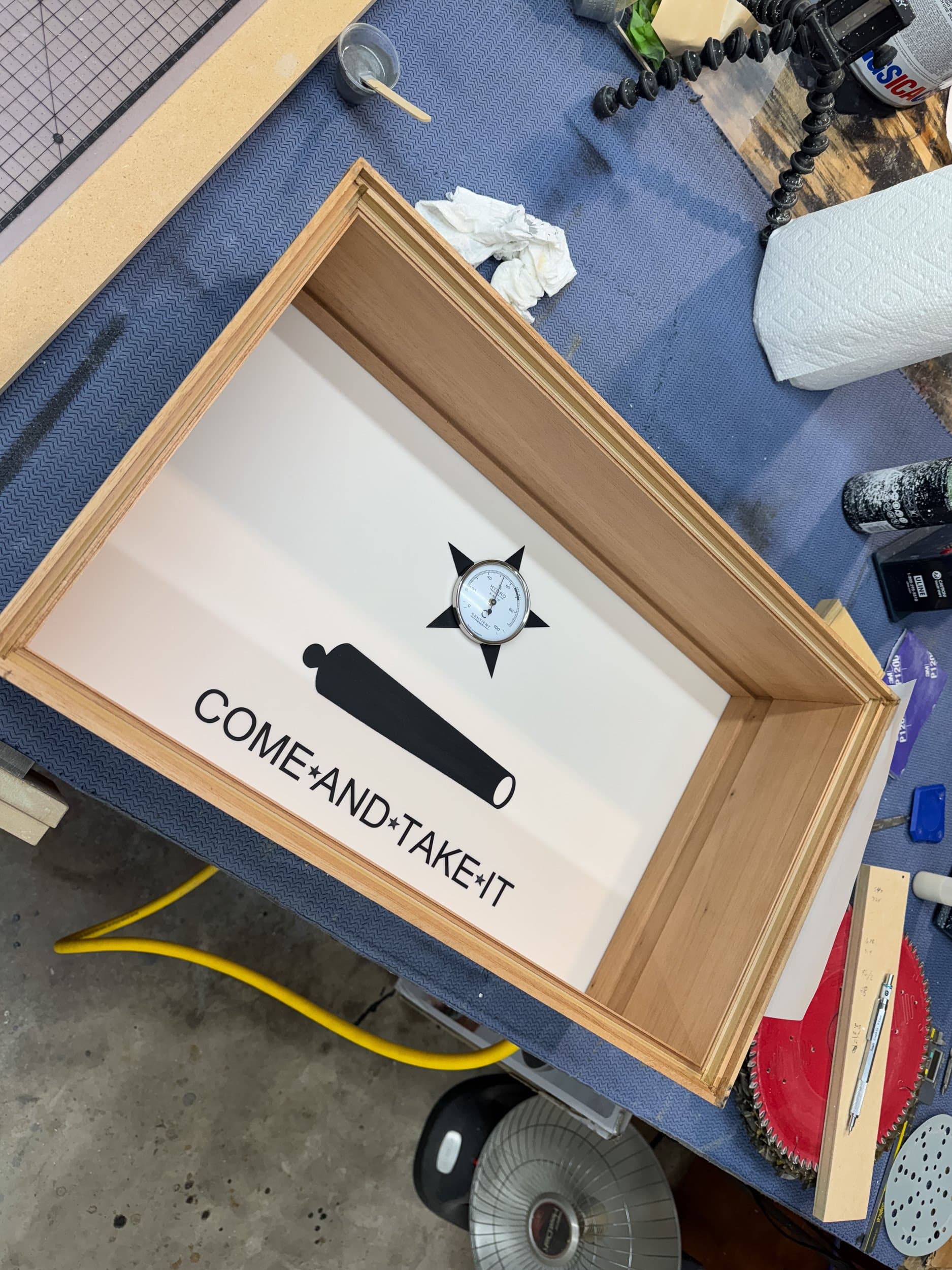 Analog hygrometer in a Centient lid beside a Texas flag inlay. Photograph, Centient.