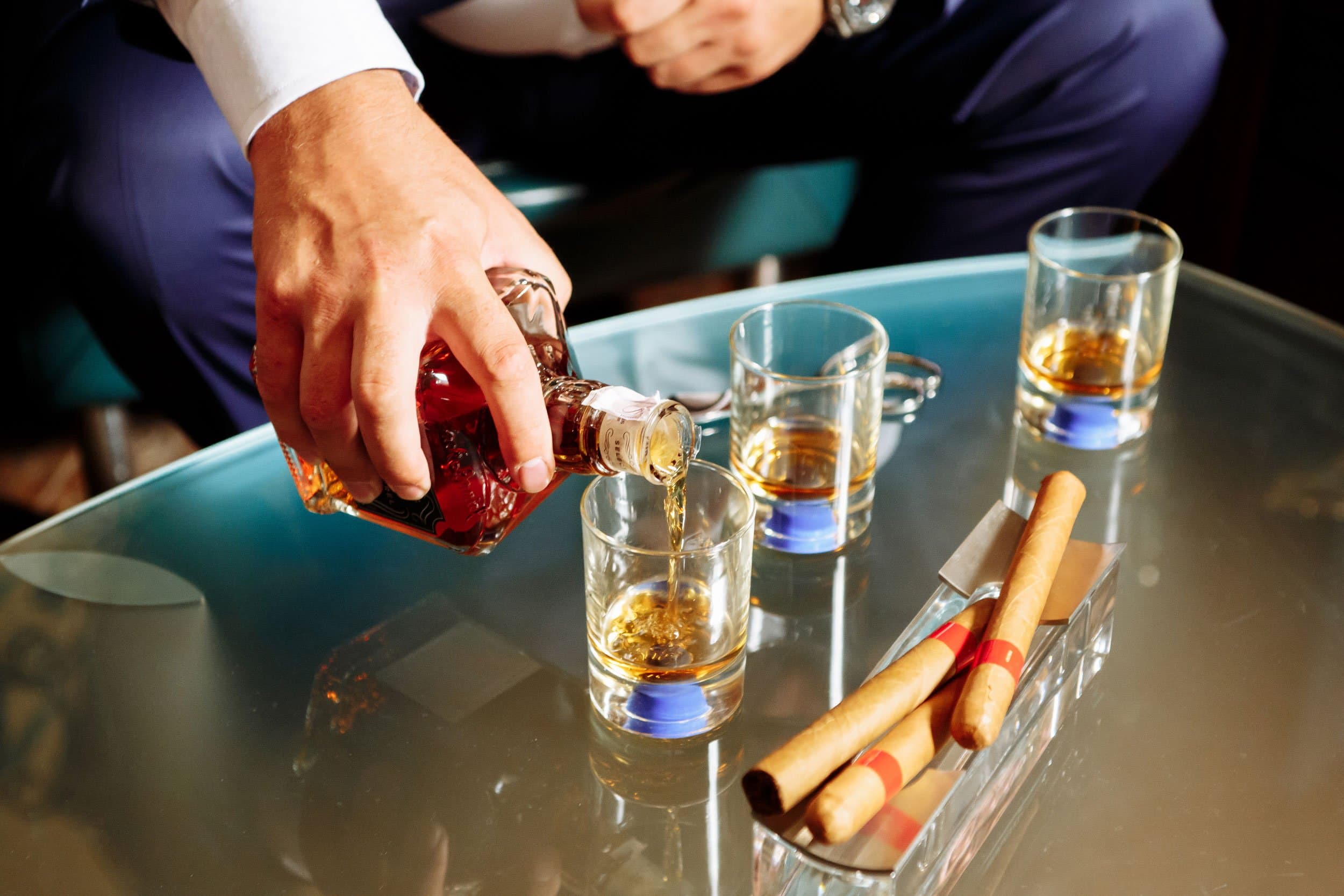 Amber spirit poured into short glasses beside cigars.