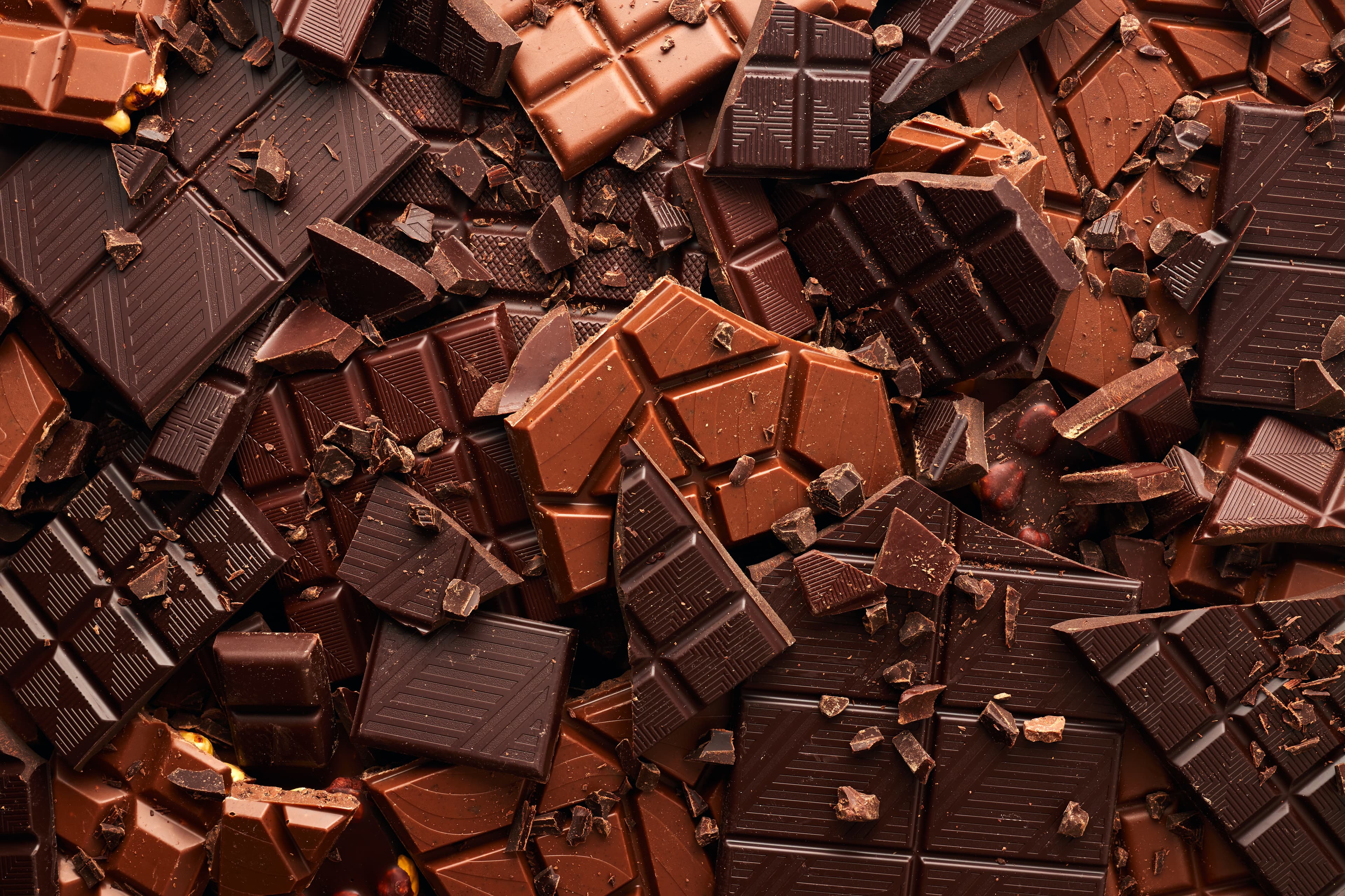 Broken dark and milk chocolate bars, some with nut inclusions.